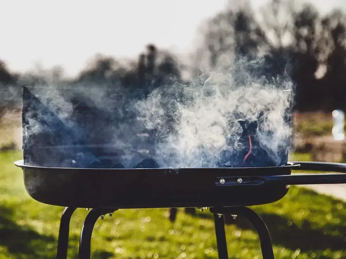 Dym unosi się z grilla, który właśnie rozpala się do grillowania. Węgiel żarzy się, gotowy na pyszne jedzenie.