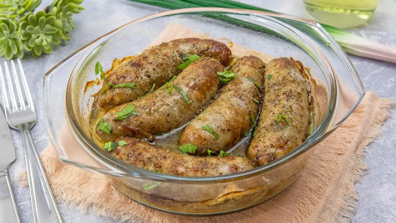 Aromatyczna, najlepsza pieczona biała kiełbasa w szklanej formie, udekorowana świeżą natką pietruszki. Idealna na obiad.
