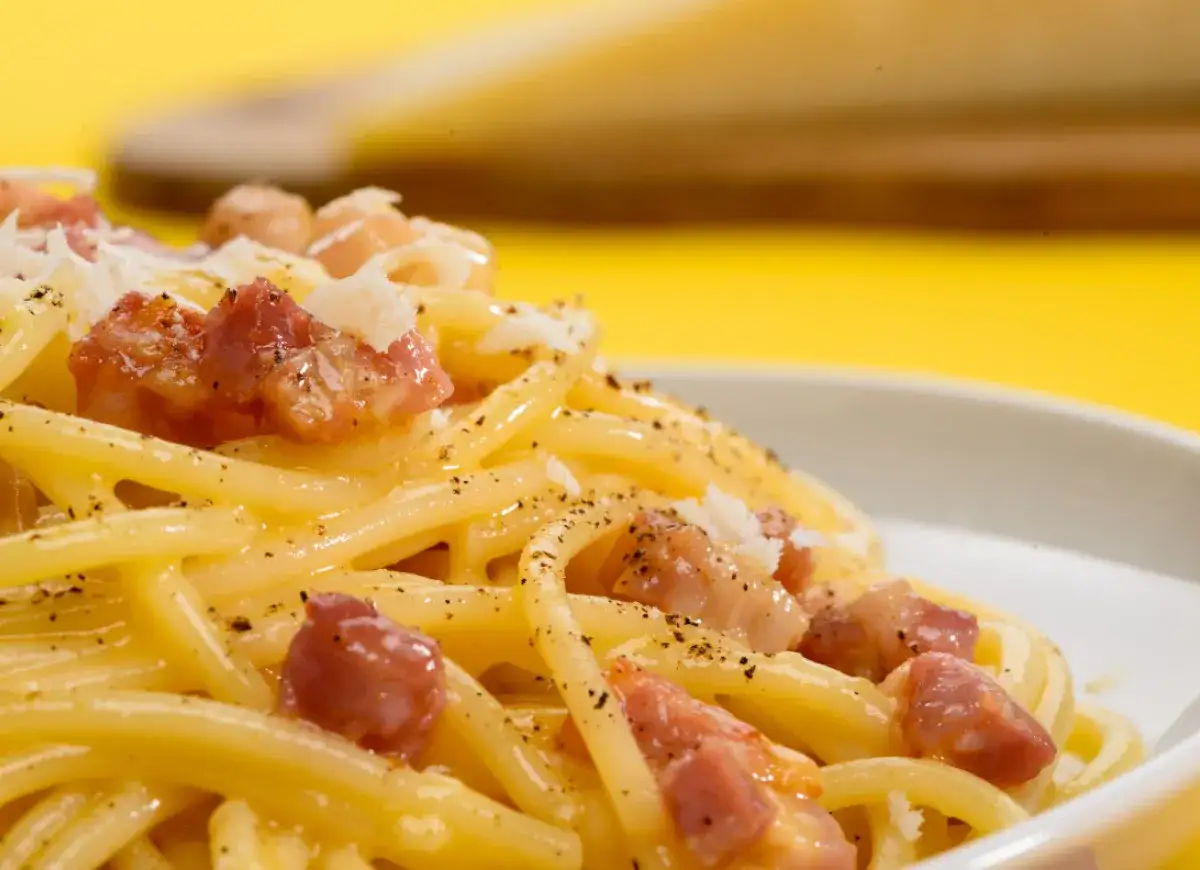 Pyszne spaghetti carbonara z kawałkami guanciale i startym parmezanem. Idealny wybór, jeśli zastanawiasz się, jaki ser do carbonary.