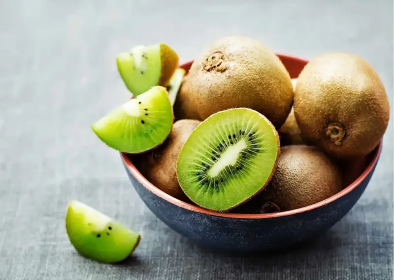 Miseczka pełna kiwi, jedno przekrojone na pół, pokazuje soczysty miąższ. Czy można jeść kiwi ze skórką? Tak, jest jadalna i pełna witamin!