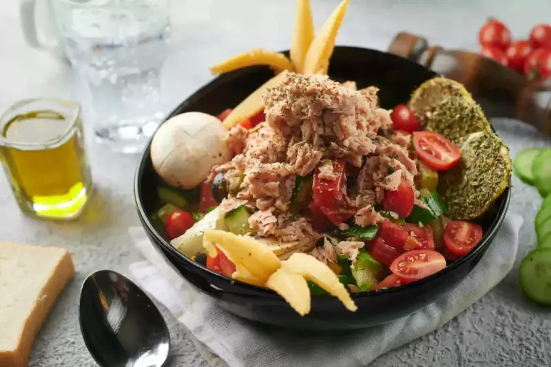 Sałatka z tuńczykiem, pomidorami i ogórkiem, inspirowana dieta śródziemnomorska przepisy. Z oliwą i pieczywem.