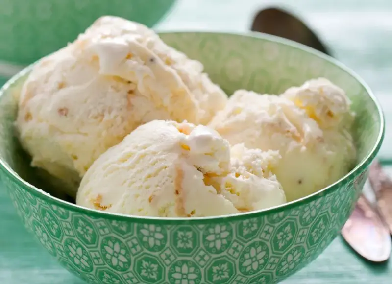 Puszyste lody z mascarpone, pełne delikatnych kawałków, kuszą kremową konsystencją w zielonej miseczce.